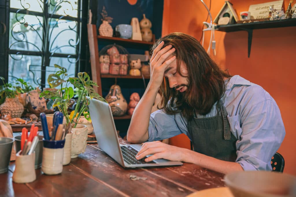 Smart Web Creative - How to Get an Affordable Small Business Website in Southern California - Business owner frustrated trying to build a DIY website on a laptop